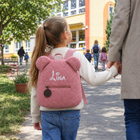 Mädchen mit rosa Teddy-Rucksack mit dem Namen Lina an der Hand auf dem Weg in den Kindergarten