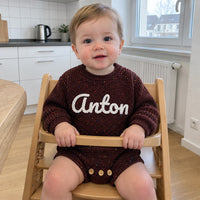 Baby im Strampler in Schokolade, Blick in die Kamera
