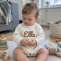 Baby im weiss melierten Strampler beim Spielen
