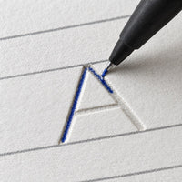 Nahaufnahme eines geprägten Buchstabens und des Stifts