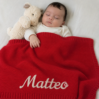 Schlafendes Baby mit gestrickter Babydecke in Rot, Name Matteo von Hand im Kettenstich bestickt