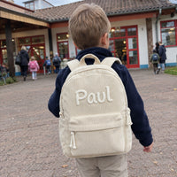 Junge mit elfenbeinfarbenem Kordsamt-Rucksack mit dem Namen Paul auf dem Weg in den Kindergarten