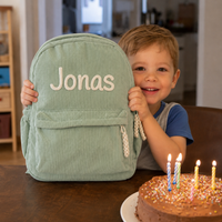 Junge hält den Kordsamt Rucksack in Salbeigrün mit besticktem Namen Jonas, Geschenk zum Geburtstag