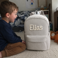 Junge im Kinderzimmer mit dem Kordsamt Rucksack in Grau, Name Elias in cremefarbener Kettenstich-Stickerei
