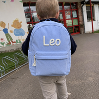 Junge von hinten auf dem Weg in den Kindergarten mit dem Kordsamt Rucksack in Hellblau, Name Leo in cremefarbener Kettenstich-Stickerei